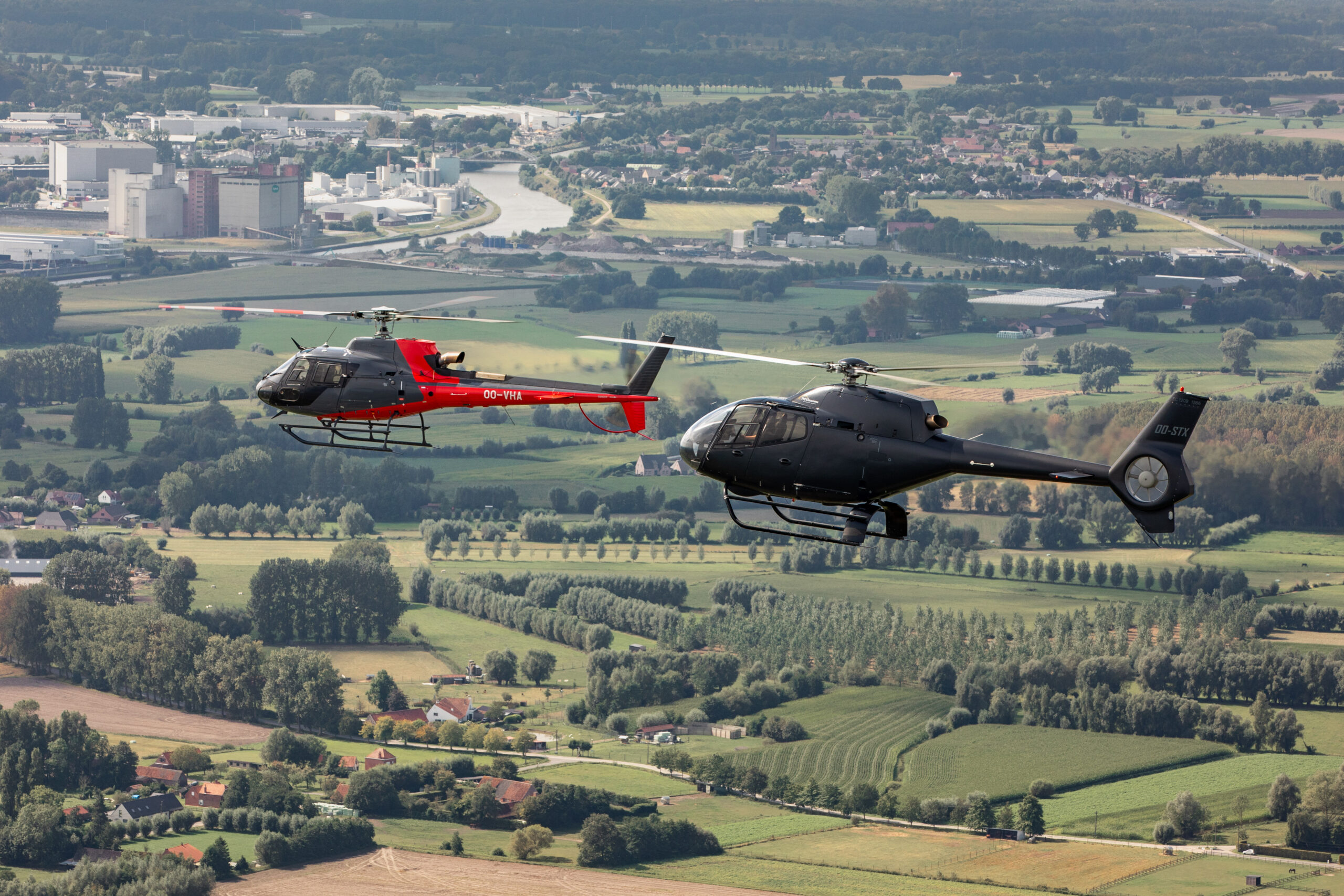Twee helikopters van Heli Business boven het Vlaamse landschap